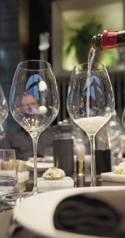 Champagne tasting, Wine glasses are on the table, stylish table setting, wine is poured from a bottle and decanter, sparkling wine bubbles, snacks, people smell the aroma and taste the wine
