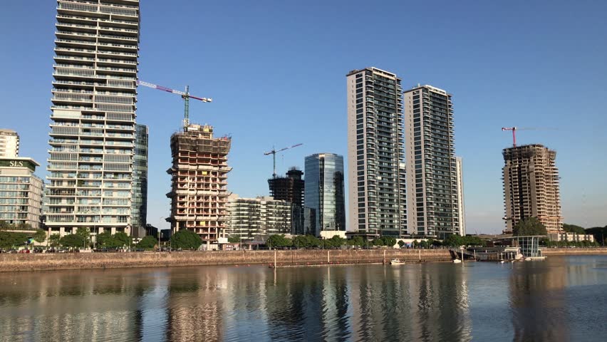 Modern buildings and construction cranes reflect in the calm waters of puerto madero, buenos aires, argentina