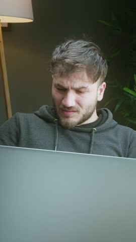 Frustrated young man struggling with bills and paperwork while working from home ,vertical video