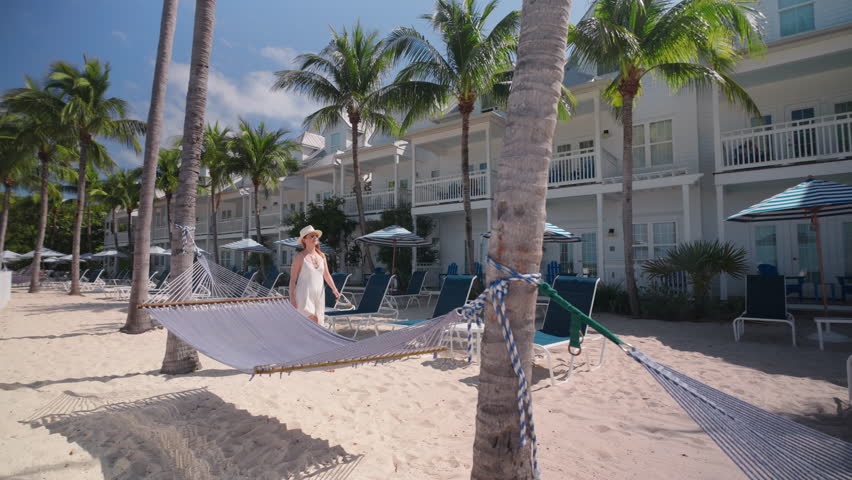 A woman strolls gracefully around a stunning hotel located in Key West, Florida, showcasing the serene beach atmosphere along with the vibrant tropical surroundings and beautiful coastal views