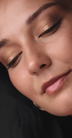 Extreme close-up of a beautiful Caucasian woman showcasing smooth skin and glowing golden eye makeup. Ideal for skincare, cosmetics, or luxury beauty promo footage.