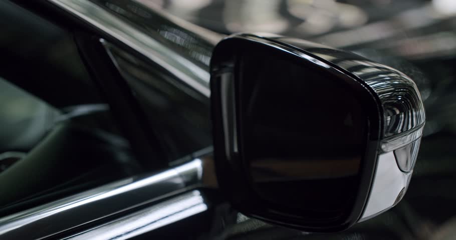 This image features a detailed close-up of a glossy car side mirror, highlighting the sleek, modern design and reflective surfaces of contemporary automotive style.