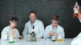Smart girl inspect colored liquid while diverse student doing experiment in STEM science class. Group of high school children working in laboratory while standing at blackboard. Creative. Edification - Powered by Shutterstock - Get 15% off with code: PIKWIZARD15