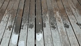 Close-up view of light rain or drizzle falling onto a weathered wooden deck or floor, creating water droplets and wet marks on the planks. Conveys a calm, quiet, or atmospheric rainy day. - Powered by Shutterstock - Get 15% off with code: PIKWIZARD15