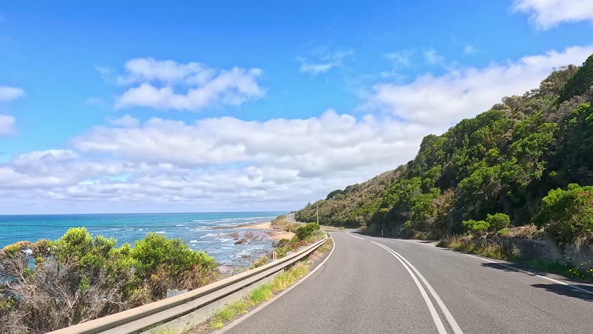 A serene drive along the Great Ocean Road with ocean views and lush greenery under clear blue skies