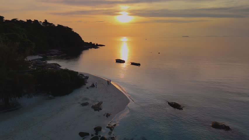Beautiful sunset casts golden hues over a peaceful beach in Koh Munnork Thailand. Couples stroll along the shore, creating romantic memories as gentle waves lap at the sand.