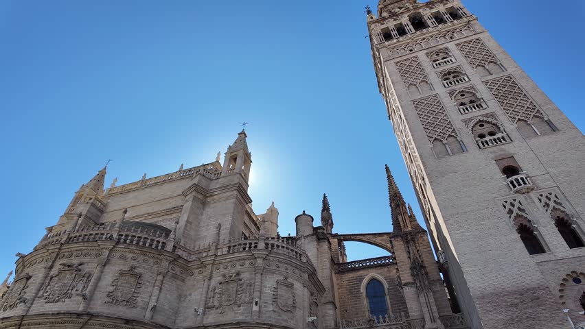 Catedral De Sevilla (Cathedral Of Seville) Is A Top Tourist Attraction In Spain. 4K Low Angle, Slow Motion Camera (Tilt Up) Towards Giralda Tower (Bell Tower).