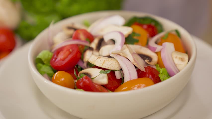 A closeup slow-motion of hands putting chicken pieces on a fresh salad in white bowl - Caesar Salad preparation