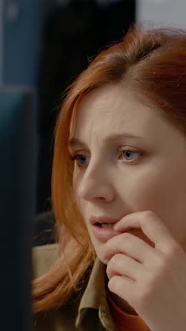 Vertical Screen: A woman appears shocked and thoughtful as she reads something unsettling on her computer. Her worried expression captures the moment of confusion and concern.