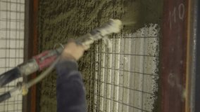 Shotcrete application. Close-up of worker's hand operating pneumatic nozzle spraying a layer of shotcrete onto polystyrene panels attached to wire mesh. House with polystyrene insulation. - Powered by Shutterstock - Get 15% off with code: PIKWIZARD15