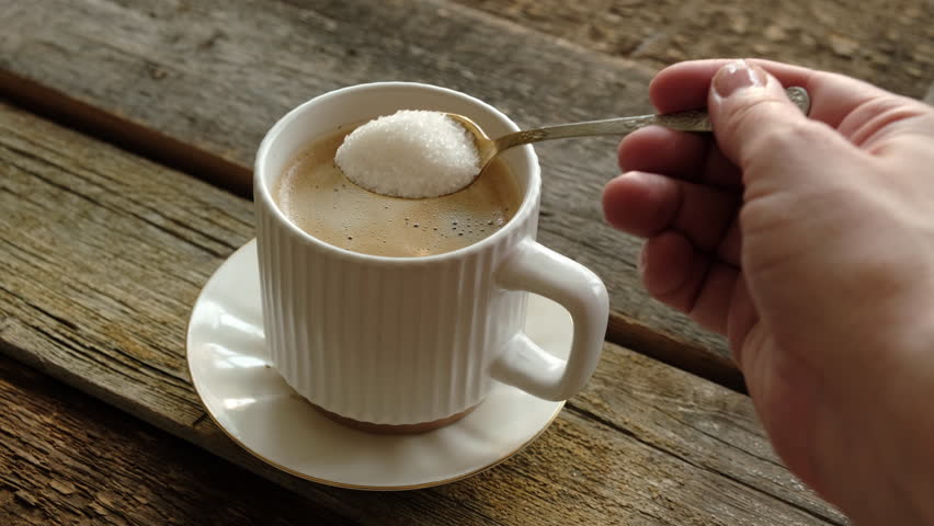 Woman drinking coffee. Hand stirring sugar in a mug of espresso coffee. Morning routine, energy boost.
