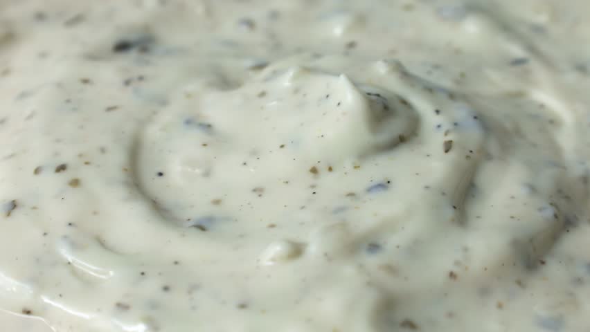 Spoon taking creamy homemade garlic cilantro dipping sauce close up