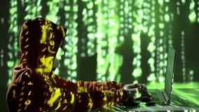 Masked hacker in hoodie types on laptop in dark room, lit by green digital code. 4K slow-motion shot symbolizing cybercrime, data breaches, and online anonymity in a tech-driven world. - Powered by Shutterstock - Get 15% off with code: PIKWIZARD15