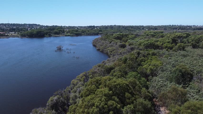 Aerial flyover Joondalup Lake tree lined shoreline, Perth Western Australia