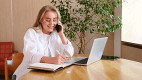 Young woman smiles during a phone call while focusing on her laptop in a cozy environment. - Powered by Shutterstock - Get 15% off with code: PIKWIZARD15