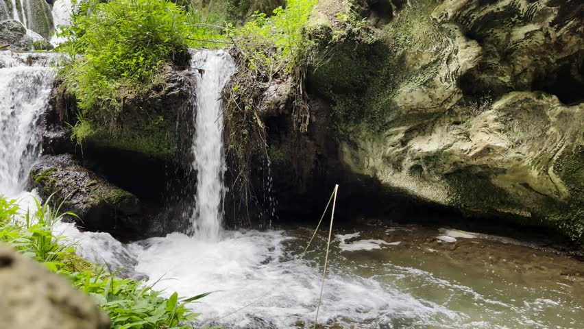 Powerful water stream from natural rocks of ancient villa in Tivoli, wet stones overgrown with bushes and moss, Italian cascade being tourist attraction and travel destination