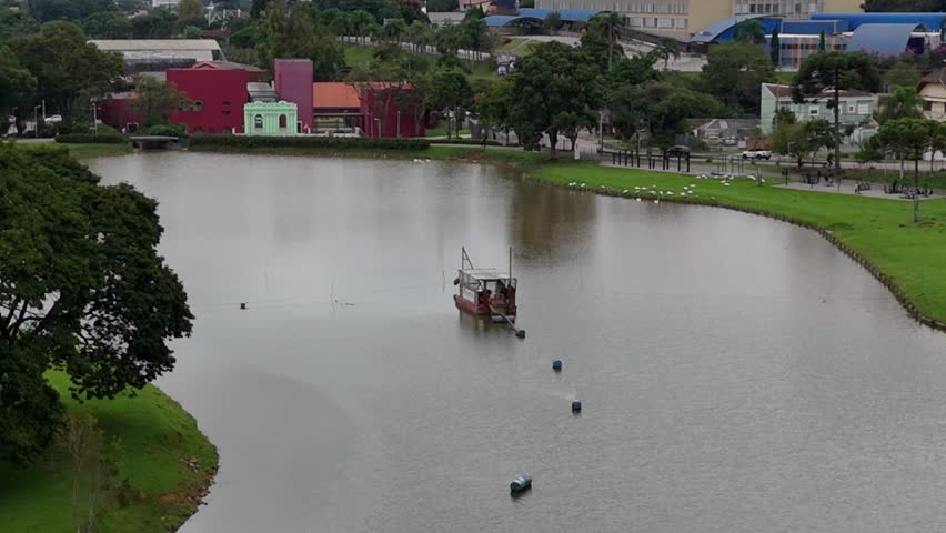 Curitiba, Paraná, Brazil - April 20 2025: Aerial drone footage over Parque São Lourenço and Belém River on a cloudy day, showing dense trees, green landscape, and urban nature scenery