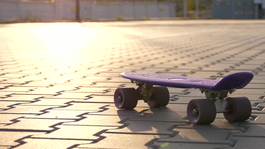 Children legs on skateboard at sunset. young skater enjoys riding skateboard. teenager skateboarding after school. Modern active pastime for youth.