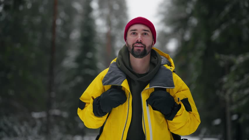Happy male tourist hiking alone in forest in winter, frontal portrait shot. Backpacking in woodland, active lifestyle and pastime in weekend, medium shot in nature, motivated hiker move forward