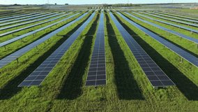 Dynamic low-level drone shot flying fast over rows of solar panels in a green field under clear daylight, highlighting renewable energy, clean technology, and sustainable power infrastructure - Powered by Shutterstock - Get 15% off with code: PIKWIZARD15