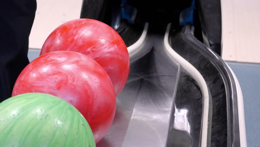 Bowling Balls are arranged neatly on a rack, all set and ready game of play Colorful bowling balls are lined up on a rack, eagerly waiting for an exciting game at the bowling alley