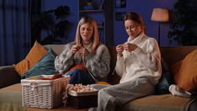 Two friends relax on a comfortable couch as they knit together, surrounded by soft yarn and a warm ambiance. Creativity flows as they share laughter and craft their handmade creations. - Powered by Shutterstock - Get 15% off with code: PIKWIZARD15