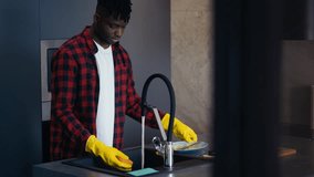 Young African American man washing dishes in kitchen, doing household chores - Powered by Shutterstock - Get 15% off with code: PIKWIZARD15