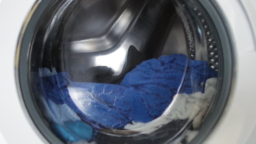 Colorful garments spinning through washing machine drum, revealing textile variety and dynamic laundry rotation process