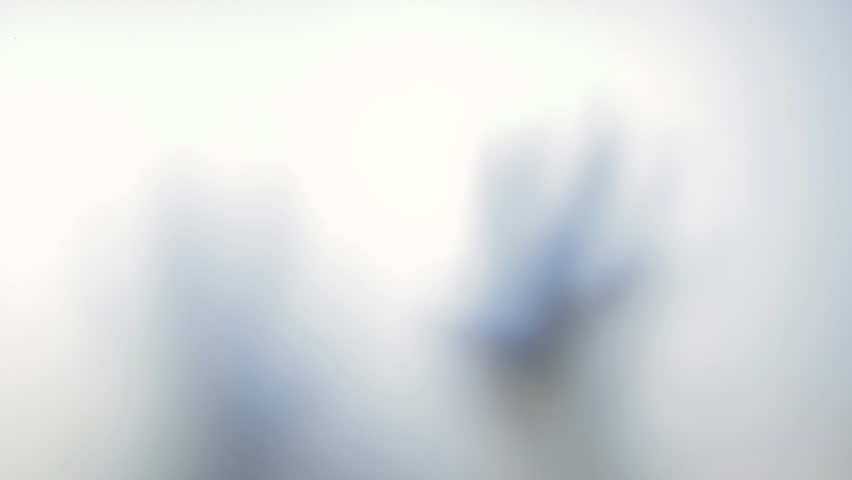 Blurred, ghostly hands pressing and sliding along frosted glass surface, creating mysterious shadowy interaction against white background