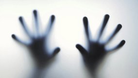 Blurred, ghostly hands pressing and sliding along frosted glass surface, creating mysterious shadowy interaction against white background - Powered by Shutterstock - Get 15% off with code: PIKWIZARD15