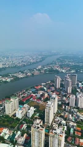 Vertical aerial: apartment buildings near the Saigon River during the day with fog in Ho Chi Minh City, Vietnam.
