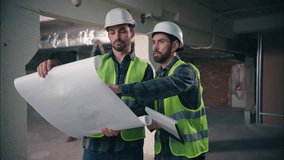 Caucasian two people men architects engineers guys males builders in helmets hardhats and vests discussing building plan project looking blueprint paper workers inspector talking document contractors - Powered by Shutterstock - Get 15% off with code: PIKWIZARD15