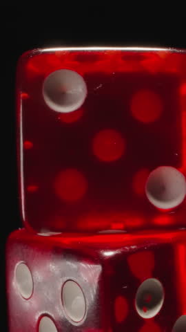 Stack of transparent red dices with certain number of white dots rotates on black background. Small cubes with spots designed for playing games macro