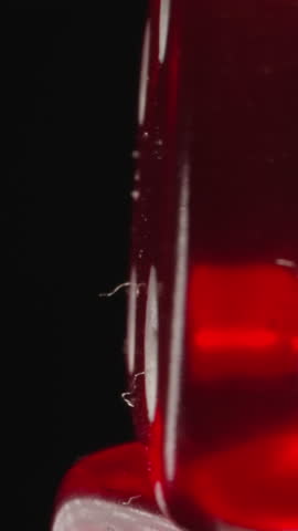 Transparent red dice with white dots reflecting bright studio light spins. Small cubes created for playing gambling games on black background macro