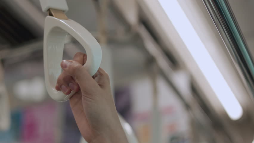 Close up woman hand holding grips a subway handle inside a modern urban transit system. This shows public transport infrastructure designed for urban daily mobility and travel convenience.