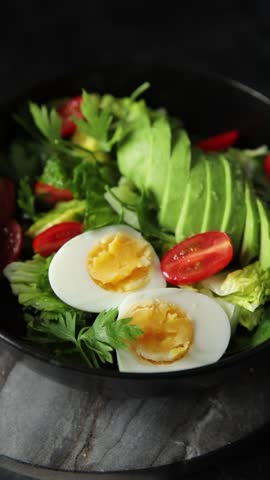 Avocado salad, boiled egg, tomato, green leaf lettuce, vegetable dish fresh delicious gourmet food background on the table rustic food top view copy space keto and paleo diet vegetarian food