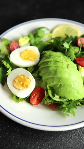 Avocado salad, boiled egg, tomato, green leaf lettuce, vegetable dish fresh delicious gourmet food background on the table rustic food top view copy space keto and paleo diet vegetarian food