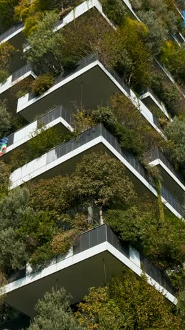 Building facade with green plants growth on the balcony. Vertical garden in Milan city, Italy. Eco friendly urban environment. Modern and ecological architecture. Vertical forest. Vertical orientation