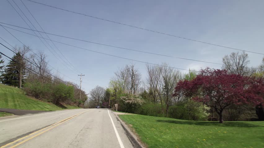 Car driving on road point-of-view POV in greater Pittsburgh, PA area in north hills of roads, infrastructure, hills, lanes, buildings, homes, and businesses close to West Virginia landscape scenary 