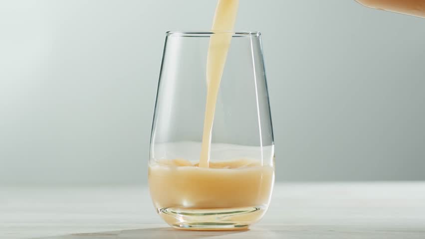Apple pear juice or cider is pouring from a bottle into a glass. Fresh drink with apples and pear on an old kitchen table. 
