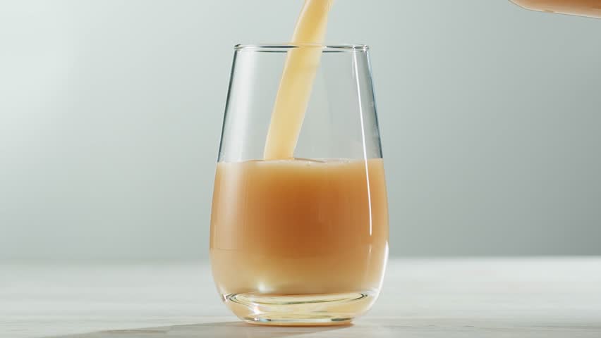 Apple pear juice or cider is pouring from a bottle into a glass. Fresh drink with apples and pear on an old kitchen table. 