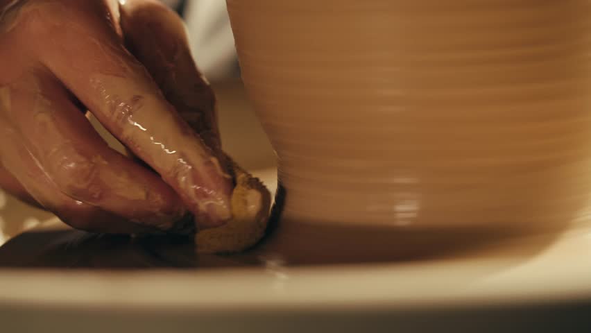 Woman potter works with clay on master class in studio. Working process in ceramic workshop. Potter making vase on pottery wheel. Handmade concept. 
