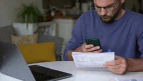 Man scanning QR code on utility bill or invoice with smartphone at home for online payment - Powered by Shutterstock - Get 15% off with code: PIKWIZARD15