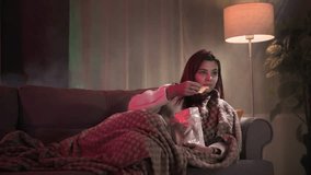 beautiful redhead woman eating potato chips and watching TV series in dark room - Powered by Shutterstock - Get 15% off with code: PIKWIZARD15