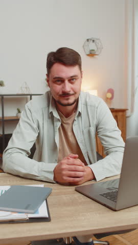 Like. Happy excited Caucasian man looking approvingly at camera showing thumbs up like sign positive something good great news positive feedback. Young guy sitting at home office table. Vertical.