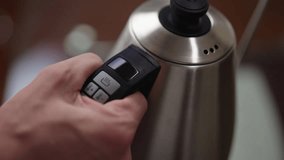 Male putting electric kettle on charger, adjusting digital controls, fine-tuning temperature for optimal brewing of tea or coffee, initiating process of boiling water for comforting morning beverage. - Powered by Shutterstock - Get 15% off with code: PIKWIZARD15