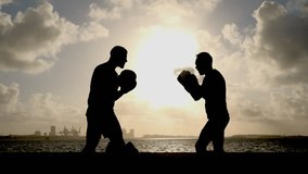 Soft unrecognizable silhouettes of two men, sportsman and trainer exercising boxing at sunrise, morning physical activity. - Powered by Shutterstock - Get 15% off with code: PIKWIZARD15