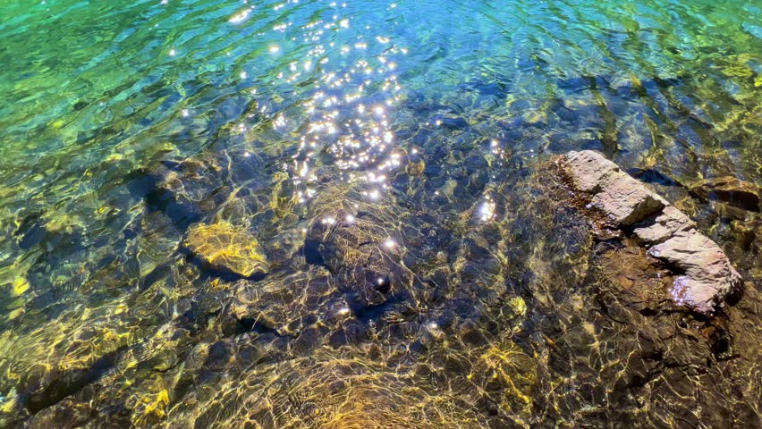 Turquoise water of the Baduk mountain lakes in a mountain valley in the mountains of the North Caucasus, on a sunny summer day. The blue sky and mountain peaks are reflected in the lake. 4К