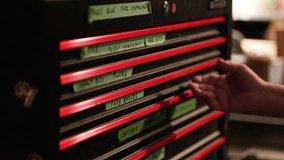 A hand reaches into a workshop toolbox filled with various tools. Each drawer is labeled, indicating the organized arrangement of essential equipment for repair or construction tasks. - Powered by Shutterstock - Get 15% off with code: PIKWIZARD15