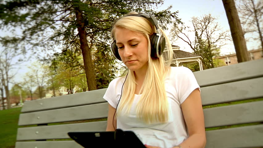 A young woman listens to her music in the park.